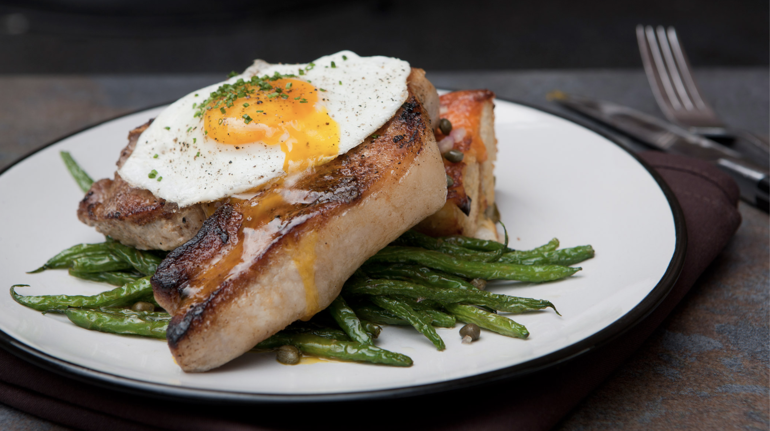 Pork chop with a fried egg on green beans
